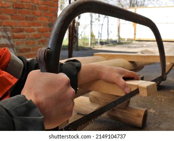 sawing off the edge of a bar in the structure of a wooden structure with an arc saw in a rural yard, a hand saw in the process of woodworking in a village, hacksaw work in a village yard