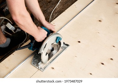 Sawing Plywood By Circular Saw. Home Repair. Hand Tool. Man Hold Equipment. Building Process. Woodworking. Safety Engineering. Without Gloves. Copy Space. Indoor. Cutting Material. Rental Instrument.