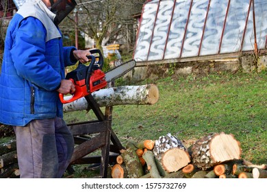 Sawing Wood With Chainsaw With Safety Glasses And Helmet In The Garden Village