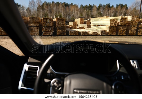Sawmill from a car window. Warehouse for sawing boards\
on a sawmill outdoors. Timber mill: storage of planed wooden\
boards. 