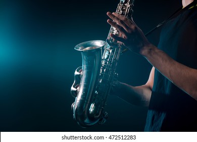 Saxophone In Magical Illumination. Musical Instrument In Male Hands With Visible Veins. Nice Silver Sax For Playing Soul Music.