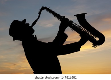 Saxophonist. Man playing on saxophone against the background of sunset