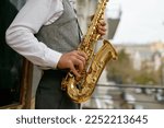 Saxophonist playing music outdoors, closeup saxophone in musician hand