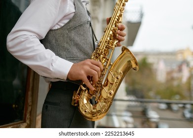Saxophonist playing music outdoors, closeup saxophone in musician hand