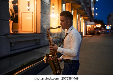 Saxophonist plays the sax on the street at night