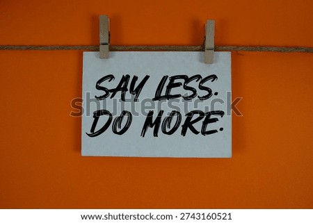 Say Less Do More text written on paper card with rope and wooden clip hanging