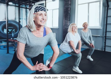 Say no to arthritis pain. Selective focus on a joyful woman smiling while lunging with a group of elderly ladies while all taking an exercise class at a fitness club. - Powered by Shutterstock