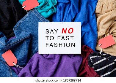 Say No To Fast Fashion Sign On Paper Card Over Heap Of Clothes.  Fast Fashion Is Bad For The Environment