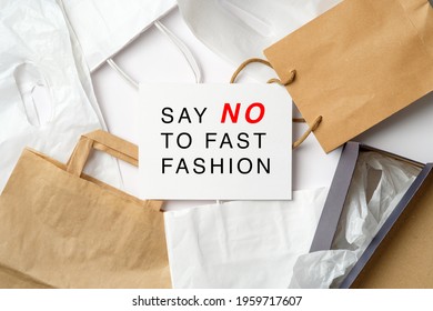 Say No To Fast Fashion Sign On Paper Card Over Heap Of Shopping Bags. Fast Fashion Is Bad For The Environment