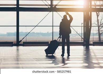 Saying Goodbye At The Airport. Silhouette Of The Traveler Waves His Hand.