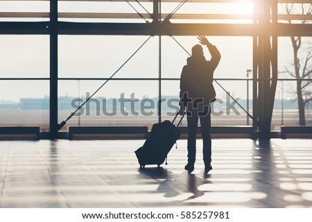 Saying goodbye at the airport. Silhouette of the traveler waves his hand.
