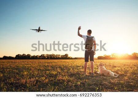 Saying hello at the sunset. Young man with his dog on the evening walk along the airport.