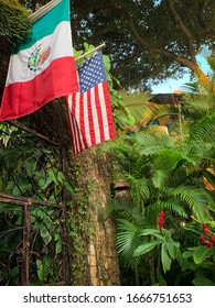 Sayulita, Nayarit, Mexico - 11 01 2019:  Mexican and USA flags hang together surrounded by tropical plants