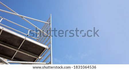 Scaffolding, metal mobile scaffold aginst blue sky background. Under construction, maintenance renovation works concept