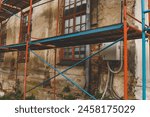 Scaffolding on a generic old tenement house, renovated historical building facade detail, closeup, nobody. Restoration industry, old architecture, real estate renovation simple concept