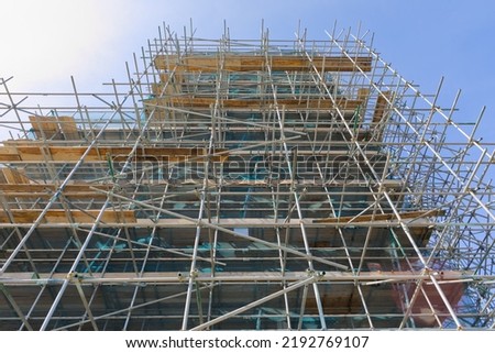 scaffolding on the outside of a large building, building not visible, looking up at construction of scaffold.
