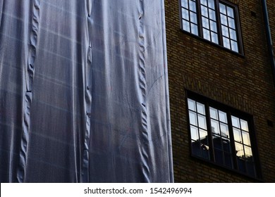 Scaffolding With White Tarp On Old Brick House