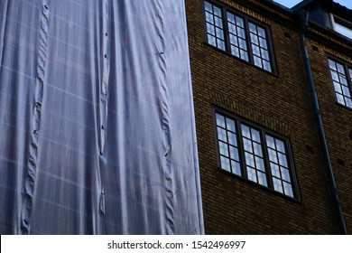 Scaffolding With White Tarp On Old Brick House