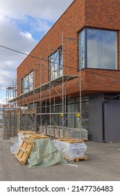 Scaffoldings At Small Commercial Building Construction Site With Material At Pallets