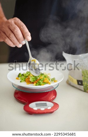 Scale, food and man with vegetables in kitchen to measure portion for calories, nutrition and balance diet. Cooking, hungry and hands of male person weigh healthy meal for lunch, dinner and supper