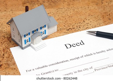 A scale house on some forms for a deed to conceptualize on the financial investment. - Shutterstock ID 80262448