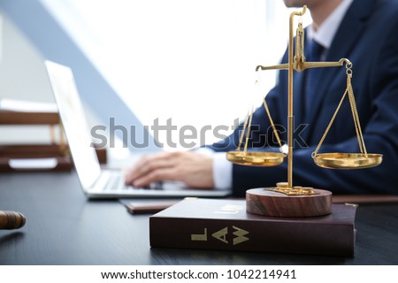 Scales of justice and juridical book on table in lawyer's office