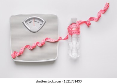 Scales and measuring tape with bottle of water on white background. Weight loss concept