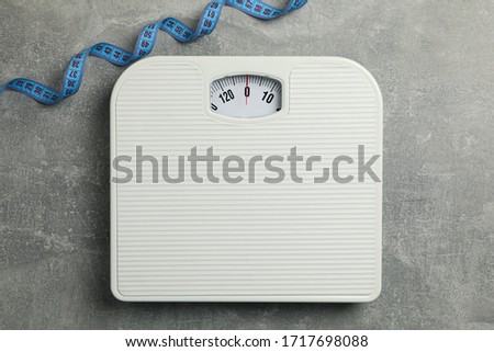 Scales and measuring tape on gray background. Weight loss concept