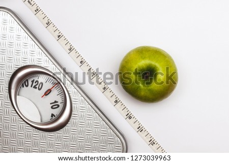 Scales for weighing with the measuring tape and green apple near them isolated on a white background. Proper nutrition. Medical starvation. Diet for weight loss concept. Free space for text. Flat lay.