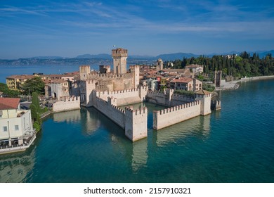 Scaligero Castle drone view. Italian castles Scaligero on the water. Flag of Italy on the towers of the castle on Lake Garda. Popular travel destination on Lake Garda in Italy. Sirmione top view.