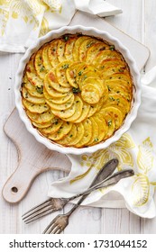 Scalloped potatoes, potato casserole with the addition of aromatic herbs  in a ceramic baking dish, top view