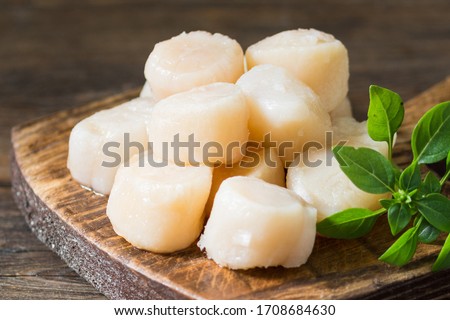Scallops on a wooden Board on a brown wooden table closeup