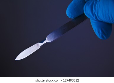 Scalpel In A Hand With Rubber Glove