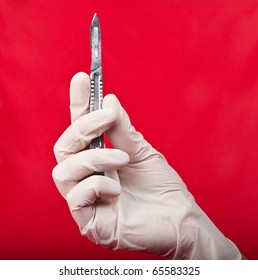 Scalpel In His Hand On A Red Background