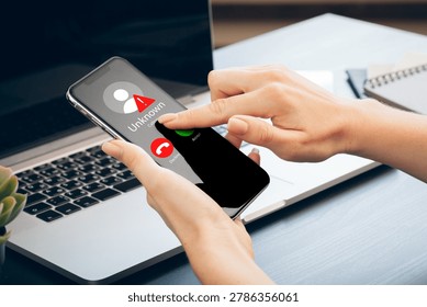 Scam call SMS message displayed on a smartphone with unknown caller ID at a work desk