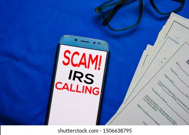 SCAM! IRS Calling Text On Smart Phone Isolated On Office Desk.
