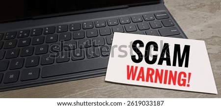 Scam Warning text printed on white paper placed on black keyboard on table, online fraud alert, cybersecurity threat, phishing scam prevention concept. 