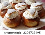 Scandanavian semla biscuits with powdered sugar topping and swirls of fresh cream