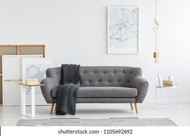 Scandi living room interior with grey, big sofa in the center and modern picture on the wall