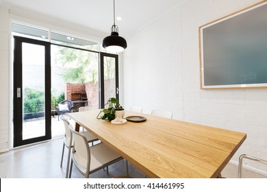 Scandi Styled Dining Room Interior With Outlook To Courtyard Through Open French Doors