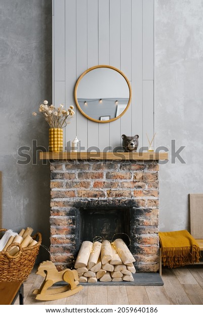 Scandinavian brick\
fireplace with wood and decor on it against the background of a\
gray wall of a country\
house
