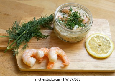 Scandinavian Food - Wooden Chopping Board With Fresh Shrimps, Dill, Slice Of Lemon And Glass Jar Of Traditional Skagen 