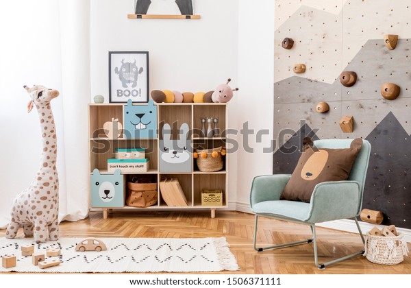 Scandinavian interior design of playroom with\
modern climbing wall for kids, design furnitures, mint armchair,\
soft toys, teddy bear and cute children\'s accessories. Mock up\
poster frame.\
Template.