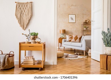 Scandinavian interior of open space with wooden bench, grey sofa, pillows, palid, picture frame, macrame, plant, books, carpet, decoration and elegant personal accessoreis in stylish home decor. - Shutterstock ID 1706401396