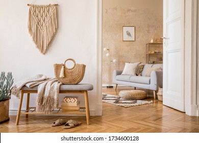Scandinavian interior of open space with wooden bench, grey sofa, pillows, palid, mock up picture frame, macrame, plant, books, carpet, decoration and elegant personal accessories in home decor. - Shutterstock ID 1734600128