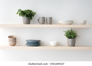 Scandinavian Minimalist Design In Interior Of Apartment, Flat For Rent Or Sale And Home Blog. Modern Plates And Cups, Kitchen Utensils, Potted Plants On Wooden Shelves, On Light Wall, Empty Space