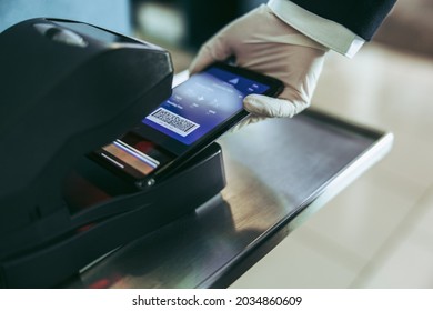 Scanning Of Boarding Pass On Mobile Phone At Airport Counter. Cropped Shot Of Airport Staff Hand Scanning Boarding Pass On Machine.