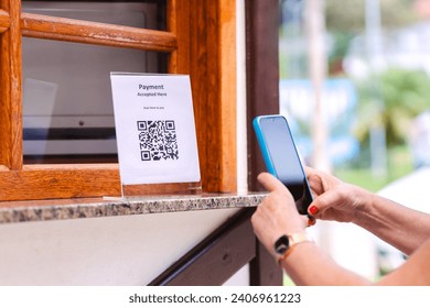 Scanning QR Code on a bar's outdoor counter using a smartphone for instant payments. Illustrates modern technology for online money transfers. 