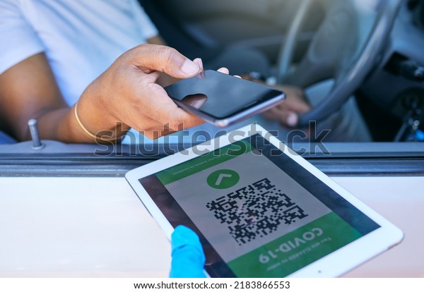 Scanning qr code to permit travel during covid\
lockdown at a checkpoint, stop or border. Person holding phone to\
scan a corona passcode, barcode or password on a tablet at a\
vaccination site