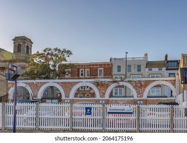 Scarborough, UK.  October 15, 2021. Five Brick And Whitewashed Arches In A Railway Station Car Park. There Are Buildings Beyond And A Tower To One Side. A Clear Sky Is Above.